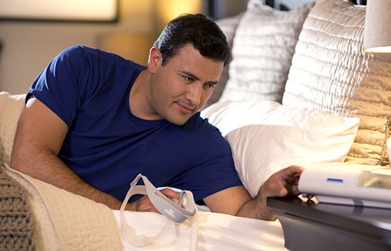 um homem deitado na cama a olhar para um dispositivo