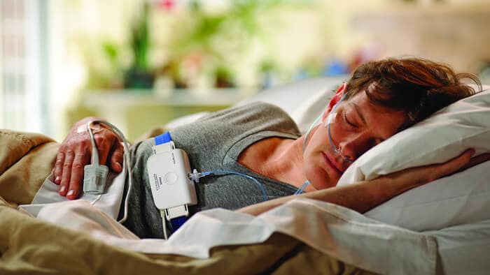 Fotografia de um homem na cama a dormir de lado utilizando um teste de sono da Philips