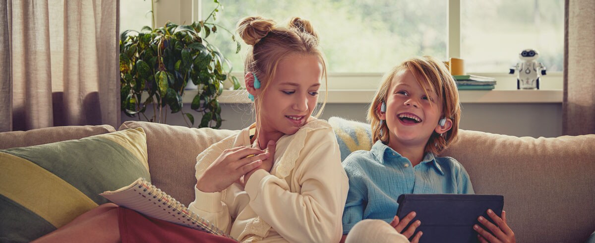 Crianças a desfrutar de um vídeo com os auscultadores open-ear para crianças Philips