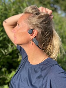 Mulher a utilizar auscultadores Bluetooth de condução óssea Philips