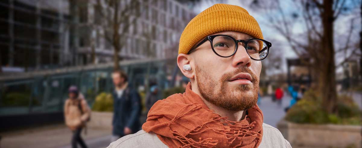 Foto aproximada de um homem usando fones de ouvido sem fio verdadeiros