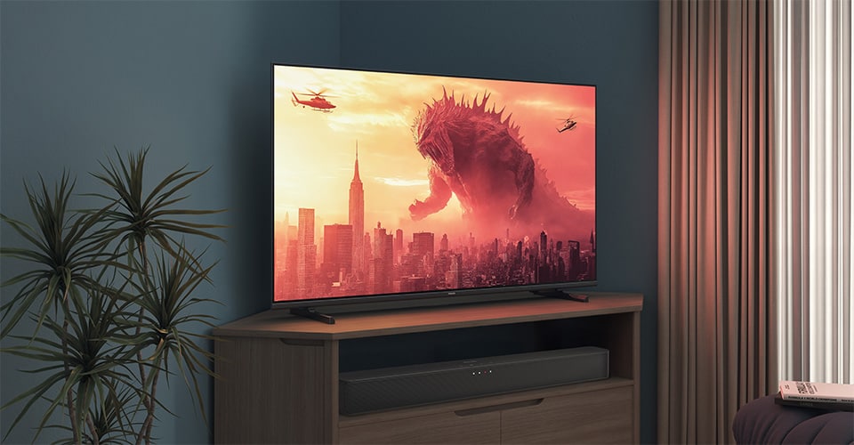 Uma TV Philips num suporte de canto exibe um filme do Godzilla