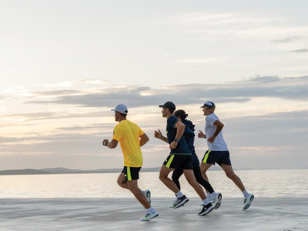 Quatro participantes na corrida estão a correr juntos na praia.