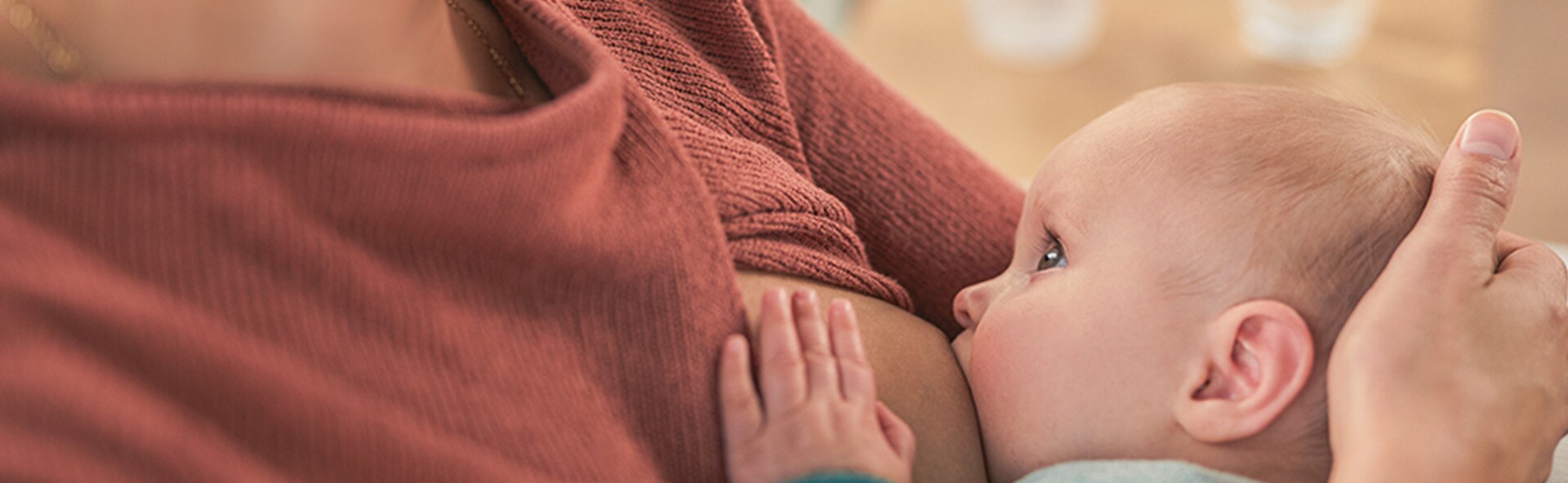 A baby sucking on their mom's breast